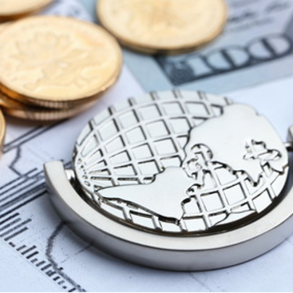 Image of a silver globe keychain beside coins and dollar bills.