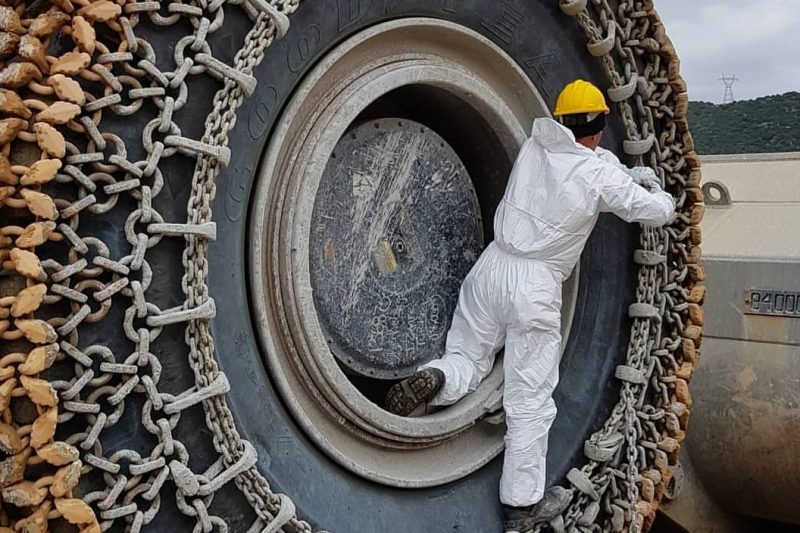Heavy equipment tire with snow traction chain in a construction site.