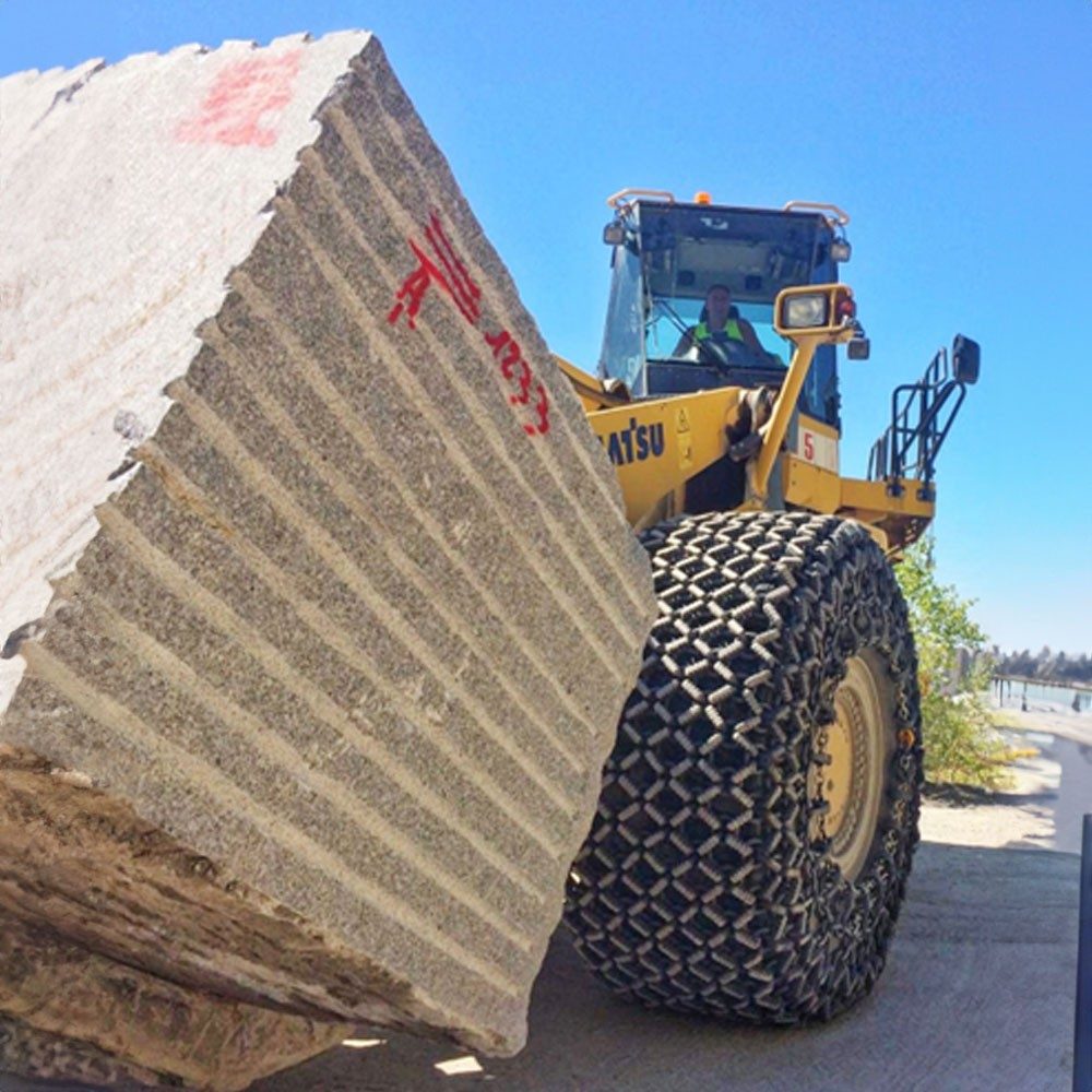 Büyük bir kepçe, ağır bir beton bloğu kaldırıyor.